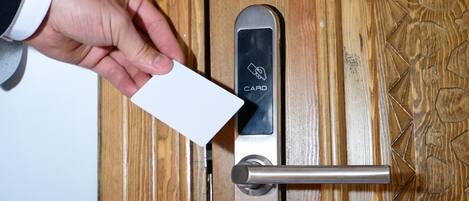 A hand inserting a card into a card reader on a wooden door.