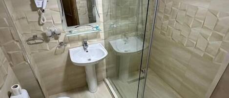 A bathroom with a toilet, sink, and glass-enclosed shower.