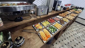 Mesa de buffet con diversos alimentos, una tostadora y una cafetera.