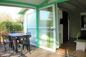 A covered patio with a table and chairs, a sliding glass door, and a small seating area inside.