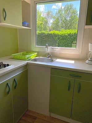 A kitchen with a window, a sink, and green cabinets.