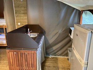 Eine kleine Küchenzeile mit Spüle, kleinem Kühlschrank und einem Holzkorpus.