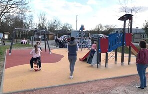 Ein Spielplatz mit verschiedenen Spielgeräten, darunter eine Rutsche und Schaukeln.