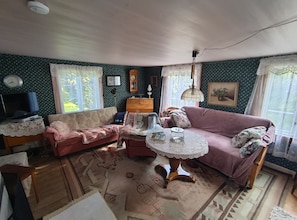Uma sala de estar acolhedora com um sofá, uma mesinha, uma televisão e papel de parede estampado.