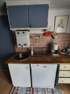 Eine kleine Küche mit Spüle, Kaffeemaschine und kleinem Kühlschrank.