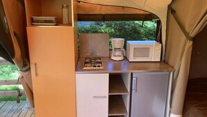 Eine kompakte Küchenzeile mit Mikrowelle, Kaffeemaschine und kleinem Kühlschrank.