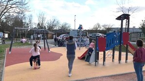 Ein Spielplatz mit verschiedenen Spielgeräten, darunter eine Rutsche und Schaukeln.