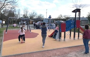 A playground with various play structures, including a slide and swings. - Camping 3 étoiles - Piscine  - ccbfghg (Mamers)