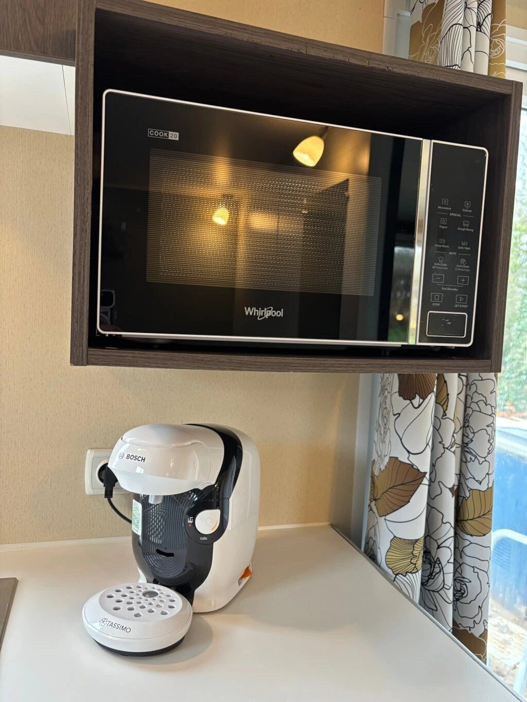 A kitchen area with a microwave above a coffee machine.