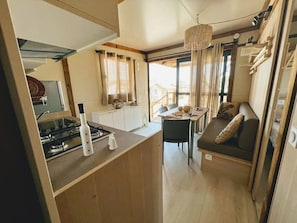 A compact kitchen with a gas stove, a dining table, and a seating area with a cushioned bench.