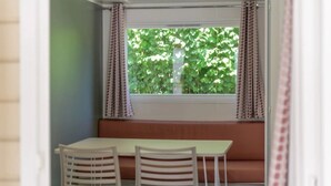 Um quarto com janela, uma mesa e duas cadeiras.
