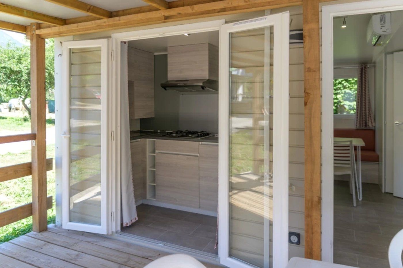 A covered outdoor kitchen with sliding glass doors, a built-in stove, and a seating area with a table and chairs.