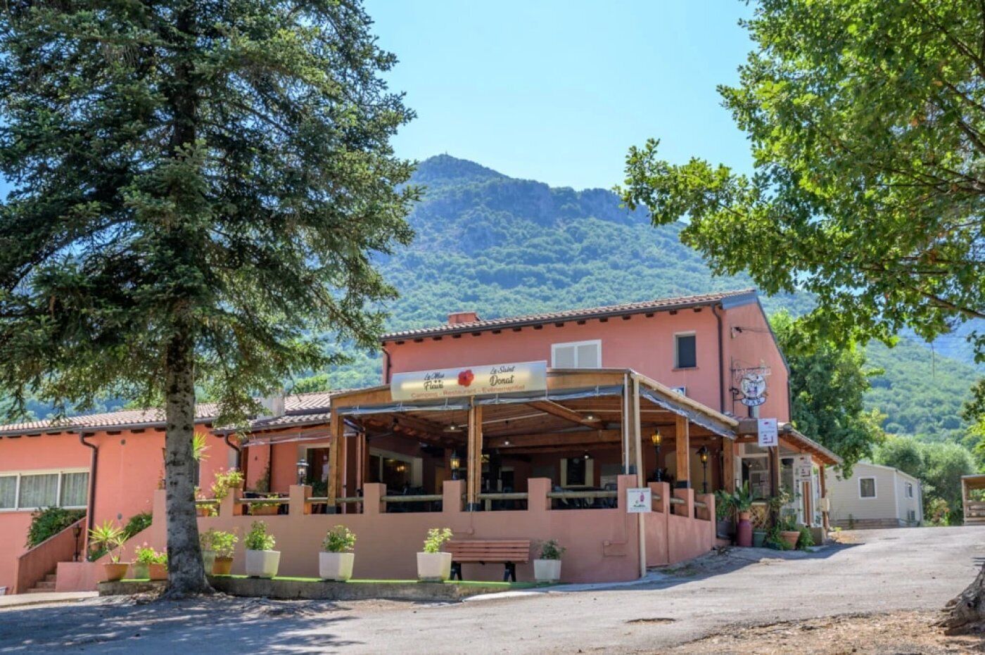 Ein Gebäude mit einem Restaurantschild, Außenbereich und einem Berg im Hintergrund.