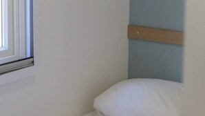 A single bed with a wooden headboard, a window with blinds, and a folded blanket on the bed. - Camping 2 étoiles - Piscine  - ccbgbhe (Sospel)