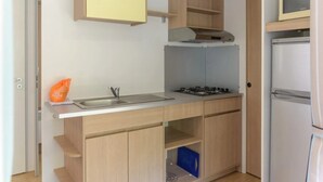 A compact kitchen with a sink, stove, and a refrigerator. - Camping 2 étoiles - Piscine  - ccbgbhe (Sospel)