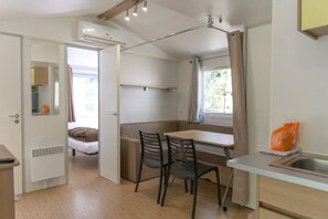 A compact room with a bed, a dining table with chairs, a small kitchenette, and a window with curtains. - Camping 2 étoiles - Piscine  - ccbgbhe (Sospel)