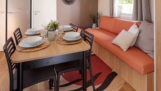 Un espacio habitable compacto con comedor, sofá, microondas y pequeña cocina.