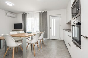 A modern kitchen with a dining area, built-in oven, and a flat-screen TV. - Apartment with large terrace (Vir)