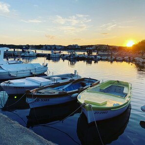 Ein Yachthafen mit vertäuten Booten, ruhigem Wasser und einem Sonnenuntergang im Hintergrund.