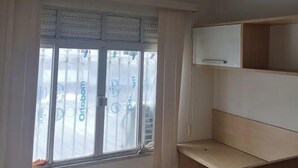 A room with a window, a ceiling-mounted air conditioner, and a wooden shelf unit. - Simplicity and Prime Location in Manaus. (Manaus)