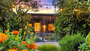 A modern building with a wooden facade, surrounded by lush greenery and flowering plants.
