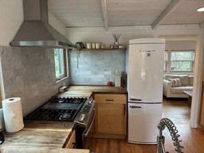 A kitchen with a gas stove, white refrigerator, wooden cabinets, and a window.