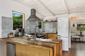 A modern kitchen with a central island, a built-in stove, and a stainless steel range hood.