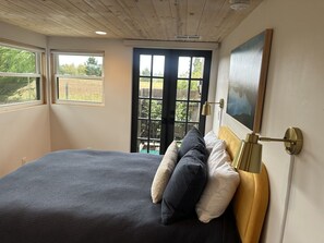 A bedroom with a bed, pillows, a headboard, a door, and a window.