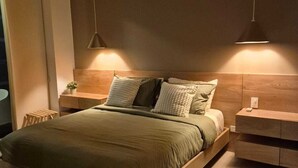 A modern bedroom with a wooden bed frame, two bedside tables, and hanging pendant lights. - MODERN APT WITH SEA VIEW AND SWIMMING POOLS 1 BEDROOM WITH BALCONY. MANZANILLO BEACH. (CARTAGENA)