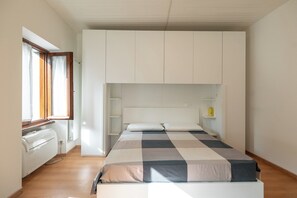 Un dormitorio con cama, armario empotrado y ventana con cortinas.