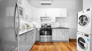 A modern kitchen with stainless steel appliances, white cabinetry, and a wooden floor.