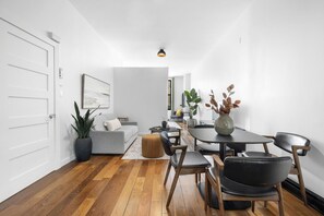 A modern living room with a grey sofa, a dining table with chairs, a coffee table, and a potted plant. - Stylish Loft in the Heart of St-Laurent (Montréal)