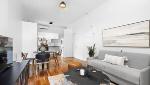 A modern living room with a grey sofa, a coffee table, and a dining area with a table and chairs.