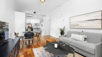 A modern living room with a grey sofa, a coffee table, and a dining area with a table and chairs.