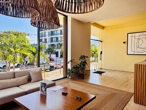 A modern hotel room with a sofa, coffee table, and a view of the street. - Designer 2BR w/ Rooftop Pool, Gym & Stunning Views (Puerto Vallarta)