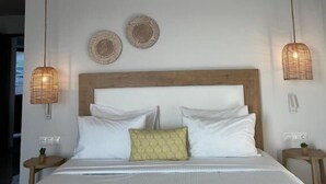 A bedroom with a bed, two wall-mounted lights, a ceiling-mounted smoke detector, and two wall decorations. - Maritime Suites (Hersonissos)