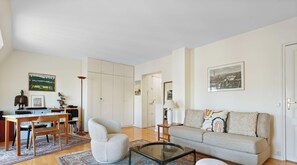 Ein Wohnzimmer mit einer Couch, einem Couchtisch und einem Schreibtisch mit Stuhl. Zwei Türen, eine zu einem Schlafzimmer und die andere zum Badezimmer.