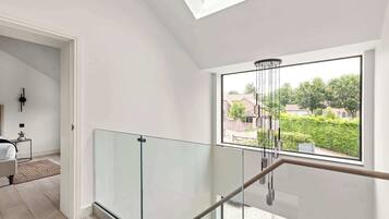 A modern interior with a glass railing, a staircase, and a view of a residential area.