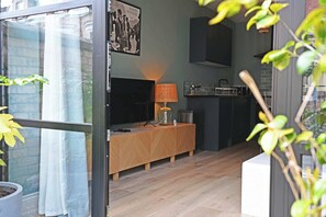 Ein modernes Wohnzimmer mit Fernseher, Holzkonsole und Lampe.