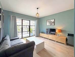 Ein modernes Wohnzimmer mit einer Couch, einem Fernseher und einem großen Fenster.
