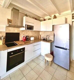 A modern kitchen with white cabinets, a stainless steel refrigerator, a Bosch oven, a microwave, and a sink. - Charming duplex with sea view (Le Gosier)