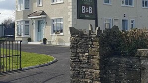 Ein zweistöckiges Gebäude mit einem Schild, auf dem 'Five Ferns House' und 'B&B' stehen, was eine Herberge kennzeichnet.