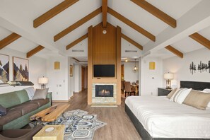 A modern room with a fireplace, a bed, a sofa, and a dining area. - Cozy Penthouse Studio with Scenic Views, Pool, Hot Tub! (Cle Elum)