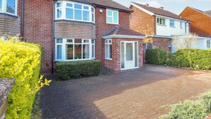 A residential area with brick houses, a paved driveway, and a small garden area. - Uphill Broadway (Lincoln)