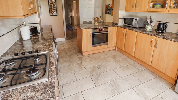 A kitchen with granite countertops, wooden cabinets, a stove, oven, microwave, and a coffee maker. - Uphill Broadway (Lincoln)