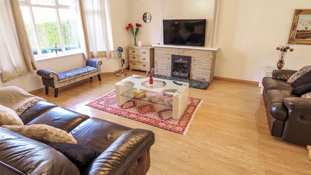 A living room with a fireplace, sofa, and television. - Uphill Broadway (Lincoln)