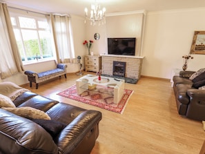 A living room with a fireplace, sofa, and television. - Uphill Broadway (Lincoln)