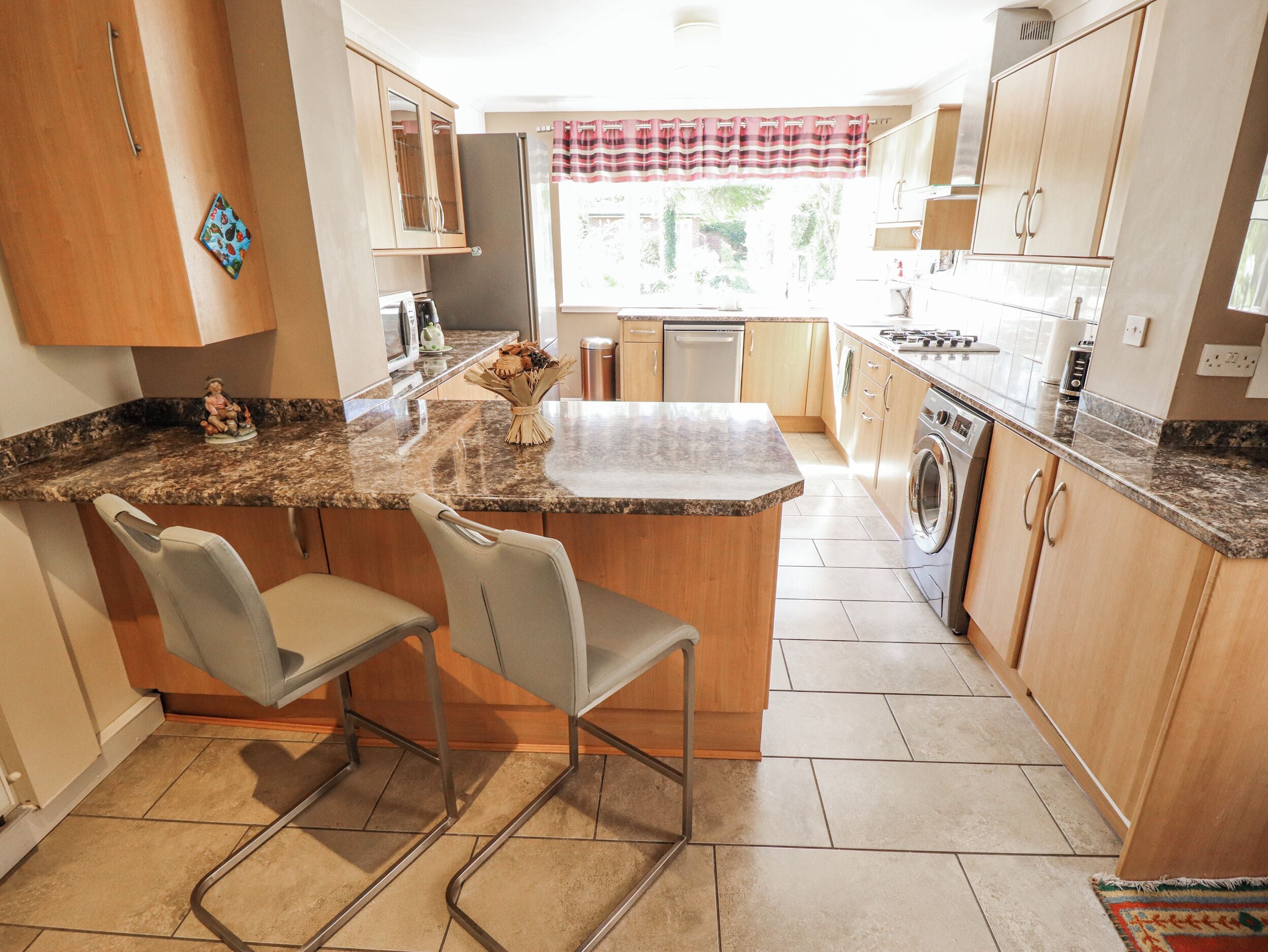 A kitchen with a granite countertop, wooden cabinets, a built-in oven, and a washing machine.