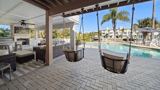 Un patio al aire libre con mobiliario de mimbre, una piscina y vistas a una zona residencial.