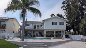 Una casa de dos pisos con piscina, un patio cubierto y un patio trasero cercado.